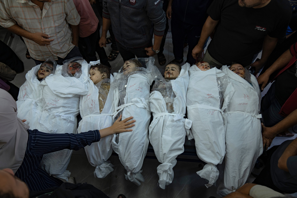 EDS NOTE: GRAPHIC CONTENT - People stand around the bodies of children killed in Israeli bombardment of the Gaza Strip, in a morgue in Khan Younis, Thursday, Oct. 19, 2023. (AP Photo/Fatima Shbair)