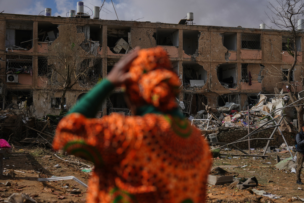 People survey a site that was struck by an Iranian missile in Dimona, southern Israel, Sunday, March 22, 2026. (AP Photo/Ariel Schalit)