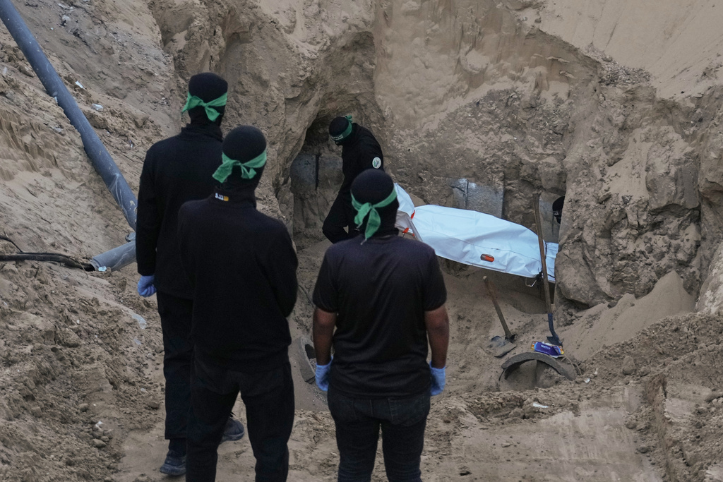 Hamas militants carry a white bag believed to contain a body, after retrieving it from a tunnel during a search for the remains of hostages in Hamad City, Khan Younis, in southern Gaza, Tuesday, Oct. 28, 2025. (AP Photo/Jehad Alshrafi)