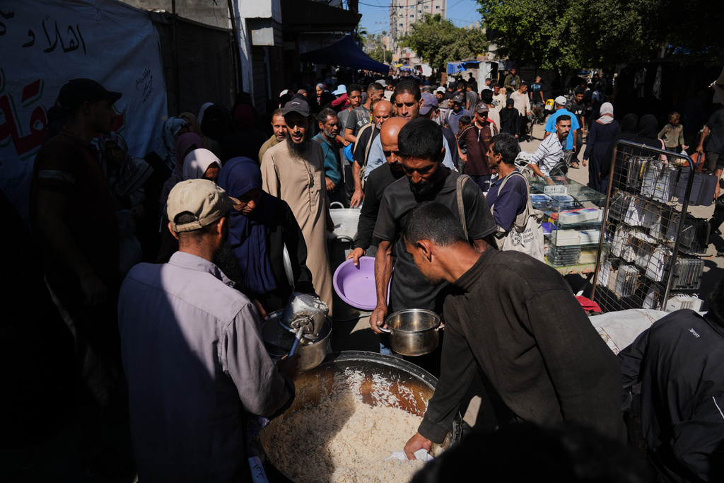 Palestinians receive donated food at a community kitchen in Deir al-Balah, central Gaza Strip, Thursday, Oct. 16, 2025. (AP Photo/Abdel Kareem Hana)