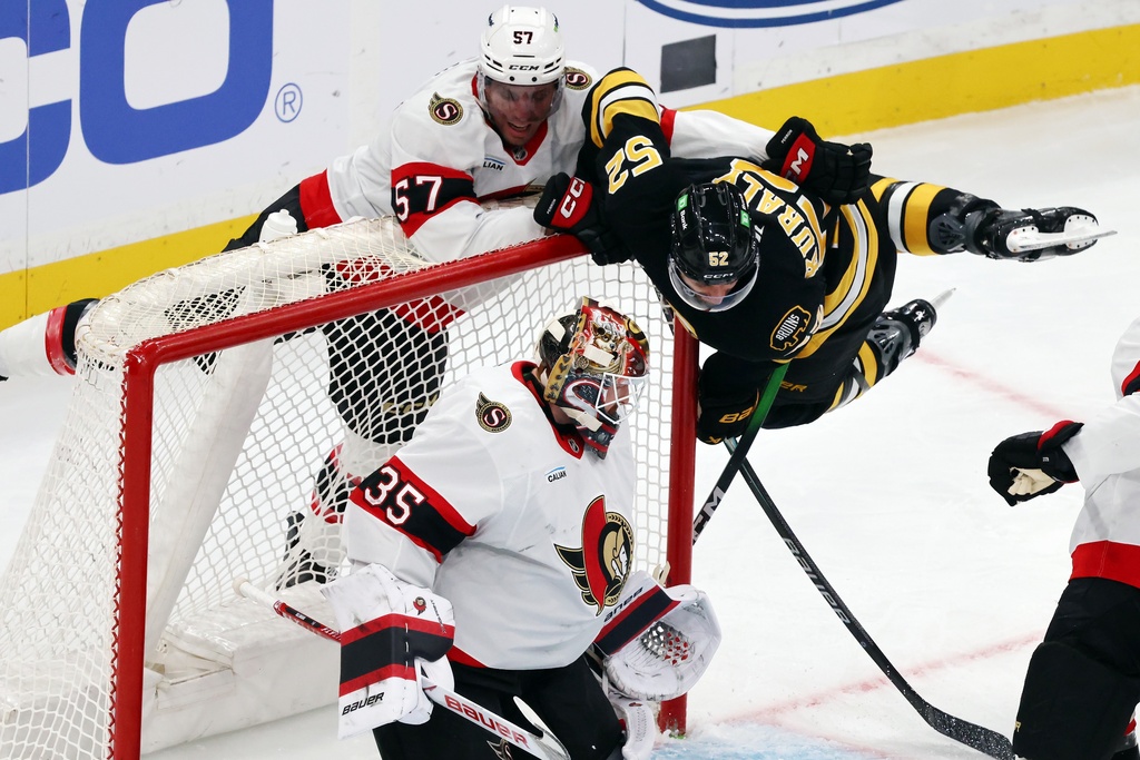 Ottawa Senators' David Perron (57) checks Boston Bruins' Sean Kuraly (52) behind Linus Ullmark (35) during the second period of an NHL hockey game, Thursday, Nov. 6, 2025, in Boston. (AP Photo/Michael Dwyer)