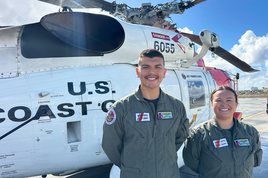 This photo made with a smartphone shows U.S. Coast Guard officer Josh Law, left, and lieutenant Miyako Miller standing in front of a rescue helicopter at the U.S. Coast Guard Air Station in Ventura, Calif., Thursday, Oct. 22, 2026. (AP Photo/Eugene Garcia)