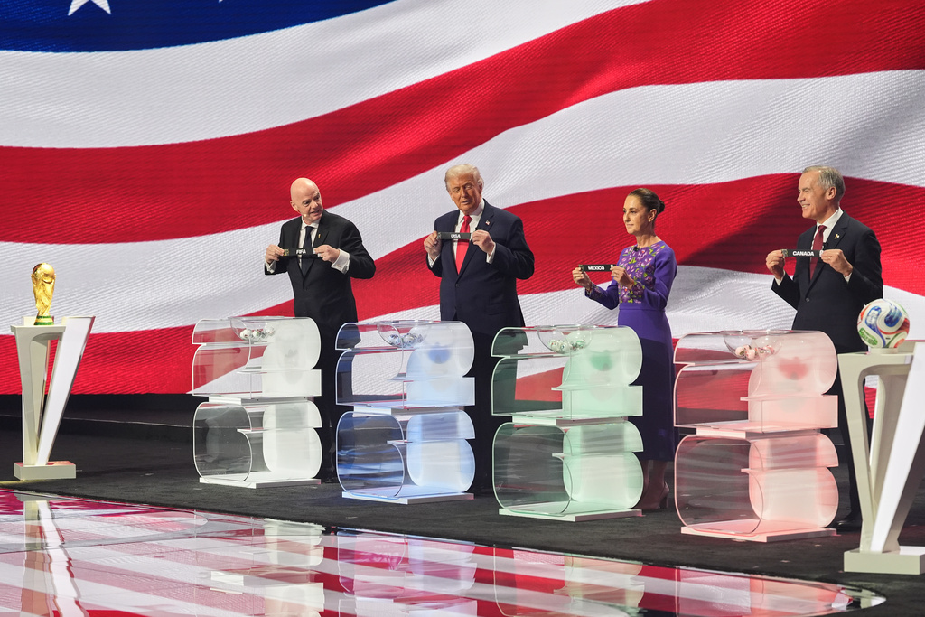 Canadian Prime Minister Mark Carney, Mexican President Claudia Sheinbaum, President Donald Trump and FIFA President Gianni Infantino hold up country names during the draw for the 2026 soccer World Cup at the Kennedy Center in Washington, Friday, Dec. 5, 2025. (AP Photo/Jacquelyn Martin)