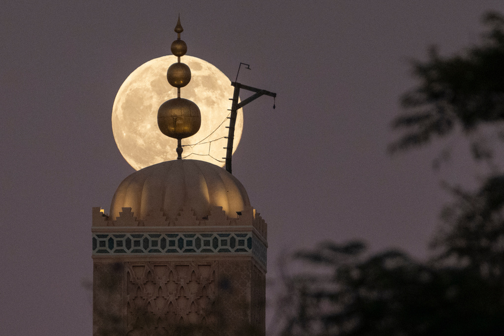 A supermoon, the last full moon of the year, rises up behind 12th century Koutoubia mosque in Marrakech, Morocco, Thursday, Dec. 4, 2025. (AP Photo/Mosa'ab Elshamy)