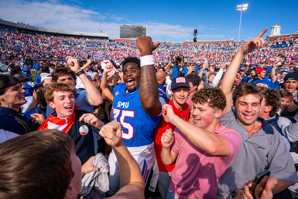 SMU offensive lineman Dramodd Odoms celebrates with fans who rushed the field after their team's 26-20 overtime win over Miami in an NCAA college football game, Saturday, Nov. 1, 2025, in Dallas. (AP Photo/Jeffrey McWhorter)