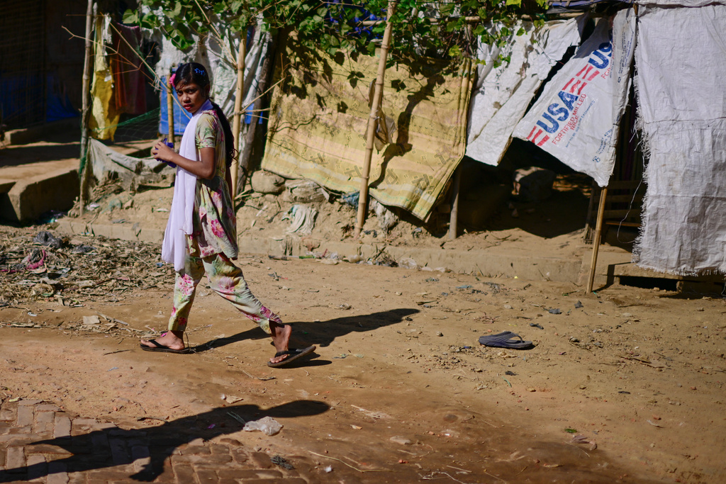 A Rohingya refugee girl walks past a hutment covered with plastic sheets marked with USA inside the Rohingya refugee camp in Cox's Bazar, Bangladesh, Tuesday, Nov. 25, 2025. (AP Photo/Mahmud Hossain Opu)