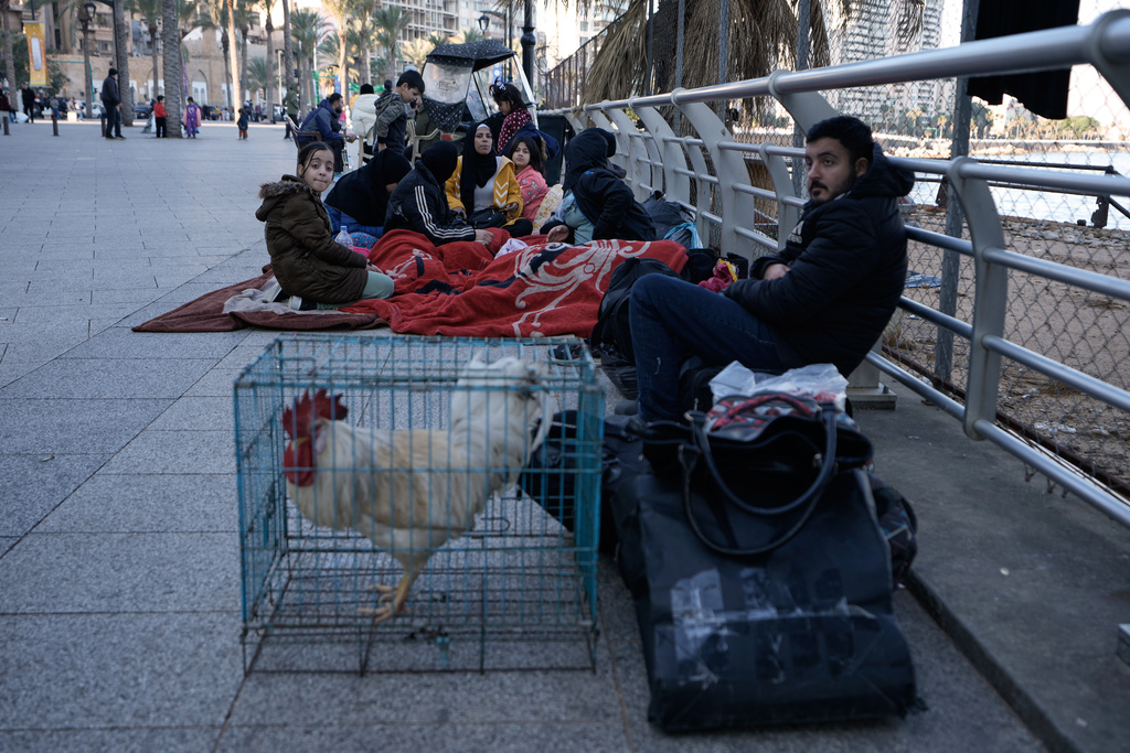 A displaced family fleeing Israeli strikes in Dahiyeh south of Beirut, sits on a sidewalk on Beirut's corniche, Lebanon, Monday, March 2, 2026. (AP Photo/Bilal Hussein)
