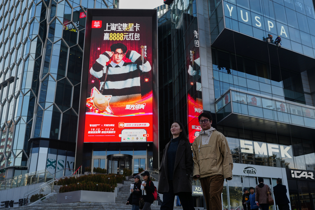 People walk by an advertisement billboard promoting Tmall's Singles' Day sale at a popular shopping district in Beijing on Nov. 10, 2025. (AP Photo/Andy Wong)