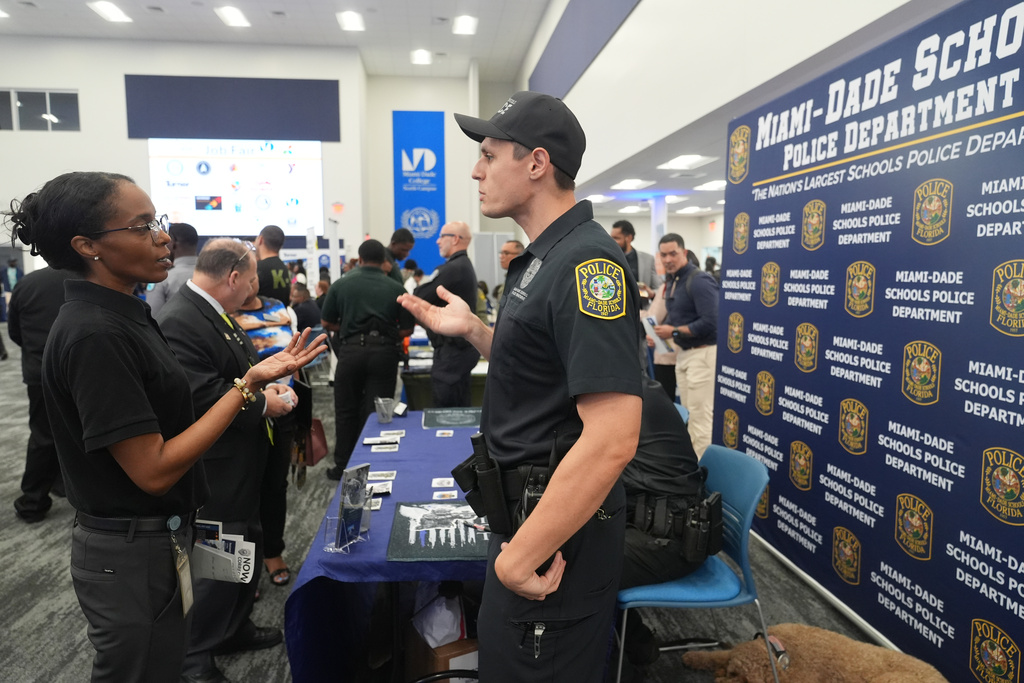 Ioan Barsan a recruiter with the Miami Dade School Police Dept. talks to a a job seeker during a job fair Wednesday, Oct. 1, 2025, in Miami. (AP Photo/Marta Lavandier)