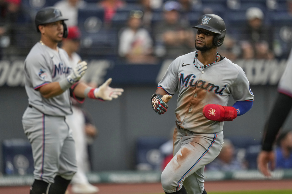 Miami Marlins' Dane Myers, right, scores past Heriberto Hernandez, left, in the fifth inning of a baseball game against the Cleveland Guardians in Cleveland, Tuesday, Aug. 12, 2025. (AP Photo/Sue Ogrocki)