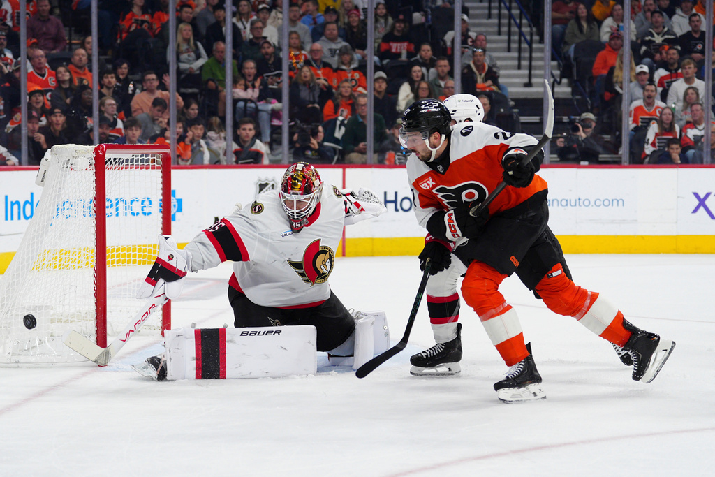 Ottawa Senators goaltender Linus Ullmark, left, makes a save as Jake Sanderson, rear and Philadelphia Flyers' Noah Cates (27) race for the puck during the second period of an NHL hockey game, Saturday, Nov. 8, 2025, in Philadelphia. (AP Photo/Derik Hamilton)