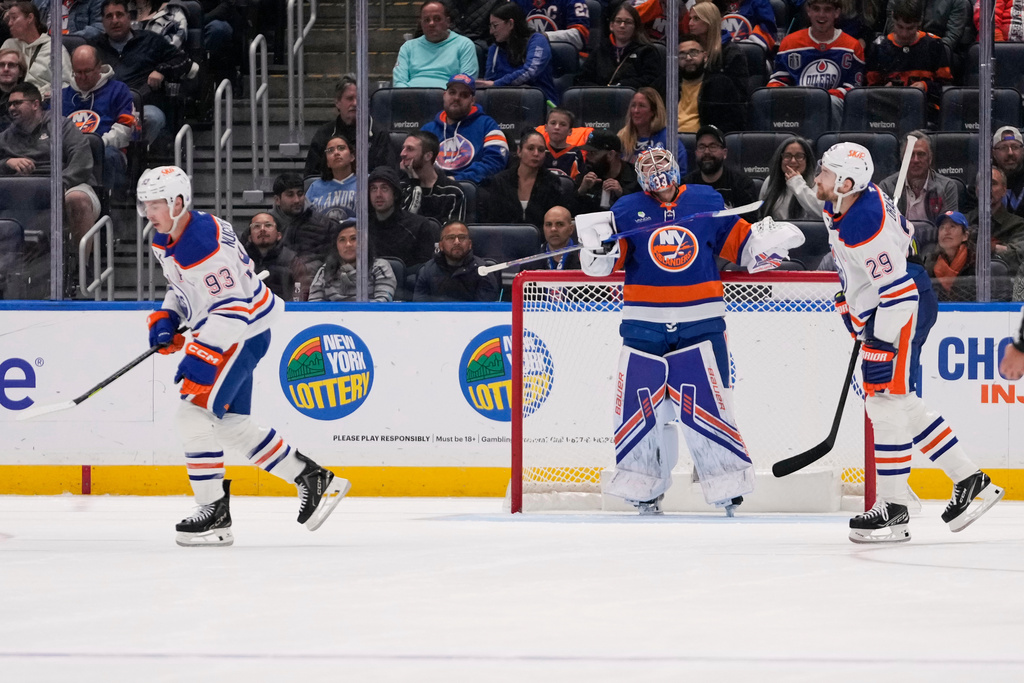 New York Islanders goaltender David Rittich, center, reacts as Edmonton Oilers' Leon Draisaitl (29) and Ryan Nugent-Hopkins (93) skate past him after Nugent-Hopkins scored a goal during the second period of an NHL hockey game Thursday, Oct. 16, 2025, in Elmont, N.Y. (AP Photo/Frank Franklin II)