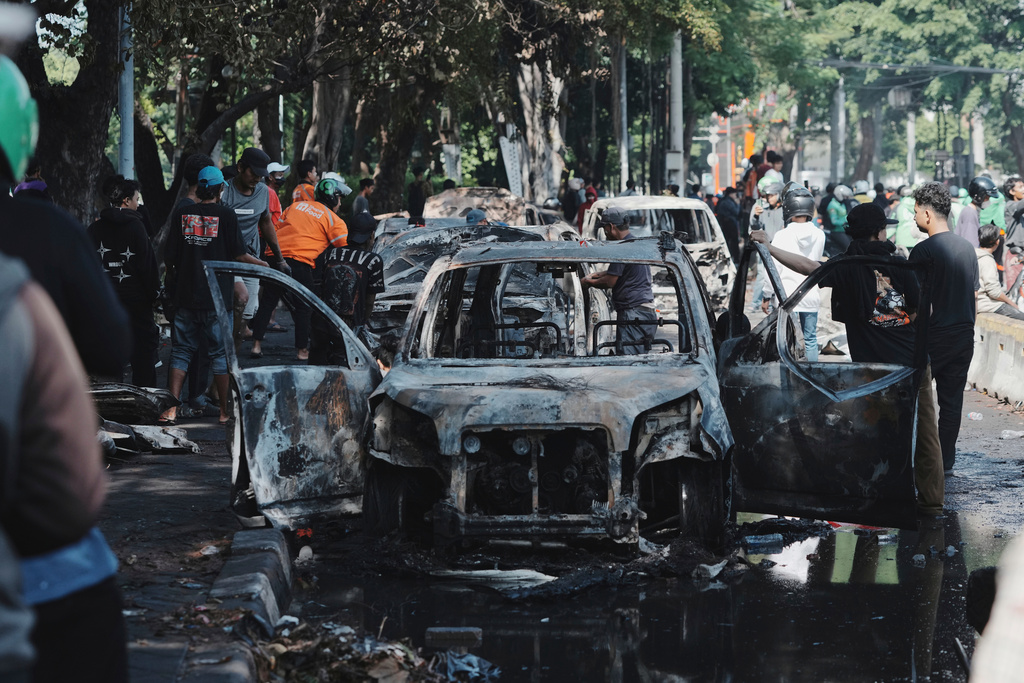 People inspect the wreckage of cars burned in Thursday's rally against lavish allowances given to parliament members, in Jakarta, Indonesia, Friday, Aug. 29, 2025. (AP Photo/Achmad Ibrahim)