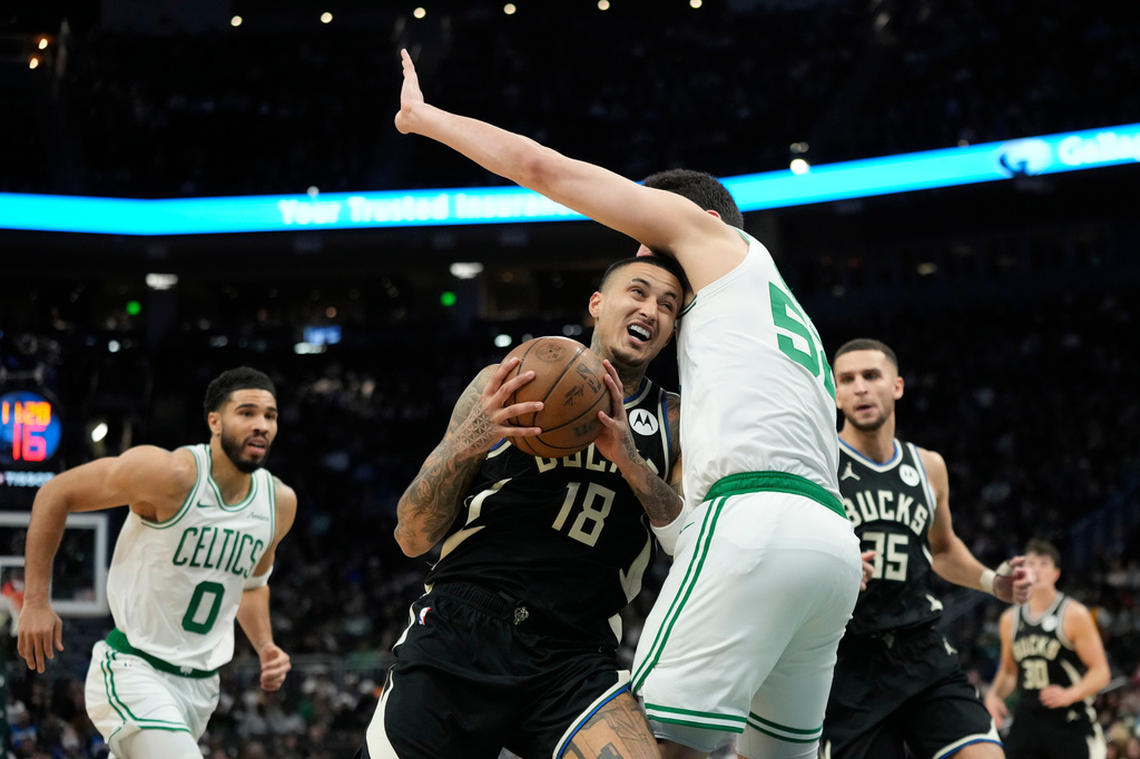 Milwaukee Bucks' Kyle Kuzma (18) drives to the basket against Boston Celtics' Luka Garza, center right, during the first half of an NBA basketball game Friday, April 3, 2026, in Milwaukee. (AP Photo/Aaron Gash)