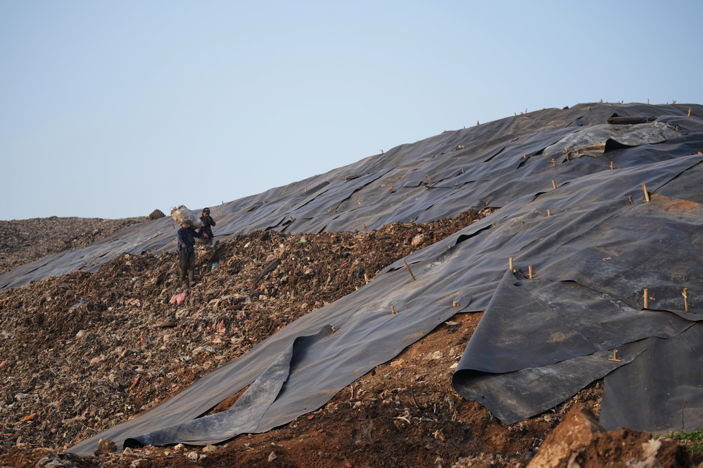Waste pickers walk near a tarped section at the Bantargebang landfill on the outskirts of Jakarta, Indonesia, Monday, July 6, 2026. (AP Photo/Tatan Syuflana)