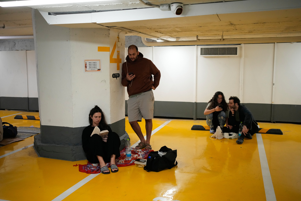 People take shelter in an underground parking garage as air raid sirens warn of incoming missiles strike by Iran, in Tel Aviv, Israel, Saturday, Feb. 28, 2026. (AP Photo/Ohad Zwigenberg)
