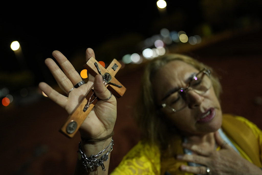 A supporter of former President Jair Bolsonaro prays during a vigil in his support near his home where he is under house arrest, in Brasilia, Brazil, Monday, Sept. 8, 2025. (AP Photo/Eraldo Peres)