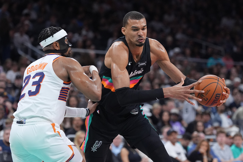 San Antonio Spurs forward Victor Wembanyama (1) drives against Phoenix Suns guard Jordan Goodwin (23) during the second half of an NBA basketball game in Austin, Texas, Thursday, Feb. 19, 2026. (AP Photo/Eric Gay)