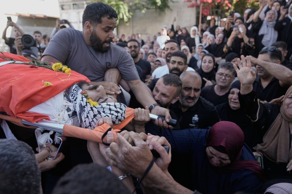 Mourners take the last look at the body of Palestinian Imad Haroun Ishtayeh, 26, who was shot and killed by Israeli forces on Sunday at a concrete barrier separating the occupied West Bank from Jerusalem, during his funeral in the village of Salem, east of Nablus, Sunday, May 31, 2026. (AP Photo/Majdi Mohammed)