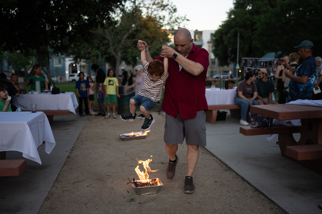 Sohrab Yassan lifts his son over a small fire as they participate in Chaharshanbe Suri, a traditional festival leading up to the Nowruz holiday, during a community gathering in the Encino neighborhood of Los Angeles, March 17, 2026. (AP Photo/Jae C. Hong)