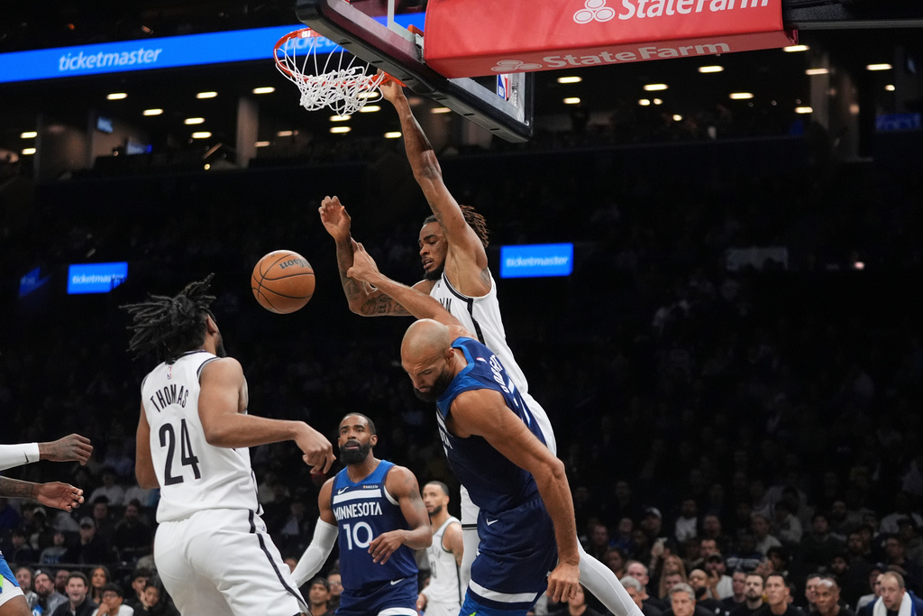 Brooklyn Nets' Nic Claxton, right, dunks the ball in front of Minnesota Timberwolves' Rudy Gobert during the first half of an NBA basketball game Monday, Nov. 3, 2025, at Barclays Center in New York. (AP Photo/Frank Franklin II)