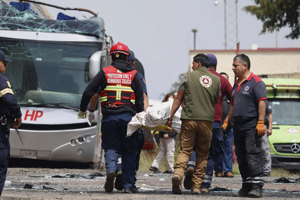 Rescue workers remove a body at the scene of a deadly accident where a freight train slammed into a double-deck bus in Atlacomulco, Mexico, Monday, Sept. 8, 2025. (AP Photo/Ramses Mercado Valdes)