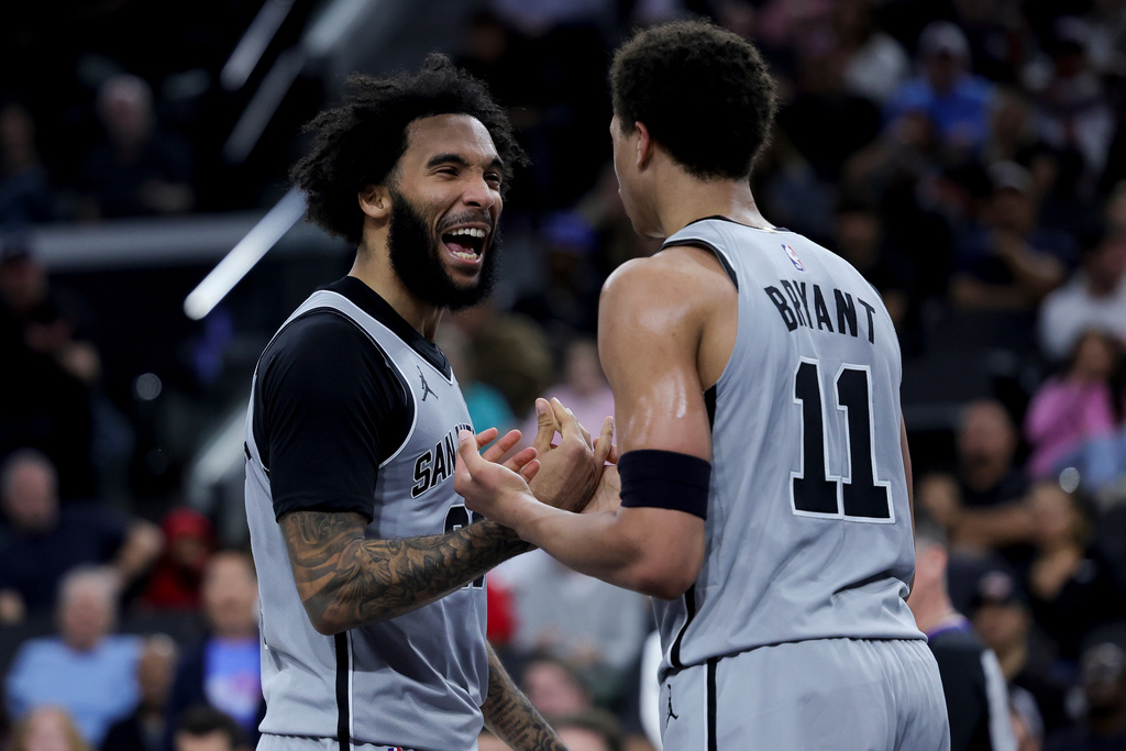 San Antonio Spurs forward Julian Champagnie, left, reacts with forward Carter Bryant (11) during the first half of an NBA basketball game against the Los Angeles Clippers, Monday, March 16, 2026, in Inglewood, Calif. (AP Photo/Ryan Sun)