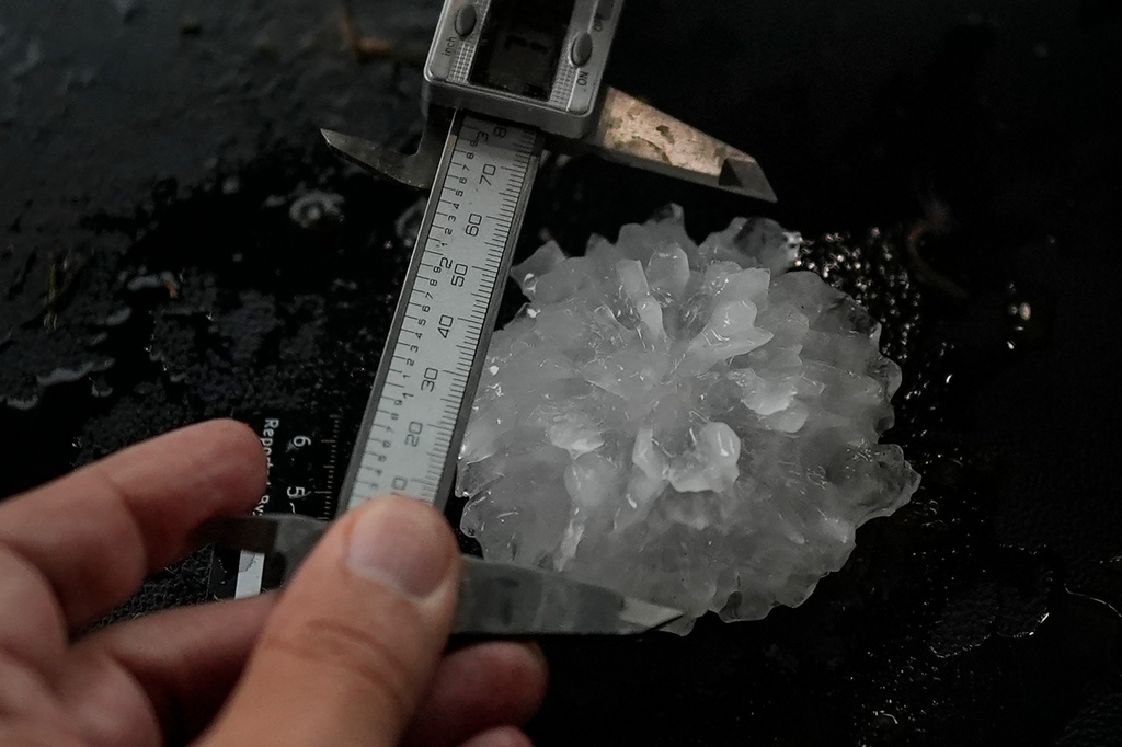 FILE - Forensic engineer Tim Marshall measures a large hail shaped like a rose between the front seats of Northern Illinois University's Husky Hail Hunter during a Project ICECHIP operation June 6, 2025, in Morton, Texas. (AP Photo/Carolyn Kaster, File)