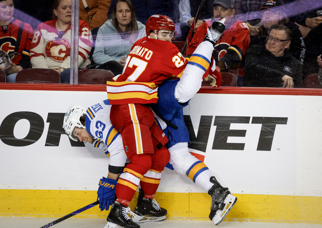 St. Louis Blues' Jake Neighbours, left, is checked by Calgary Flames' Matt Coronato during the third period of an NHL hockey game in Calgary, Alberta, on Wednesday, March 18, 2026. (Jeff McIntosh/The Canadian Press via AP)