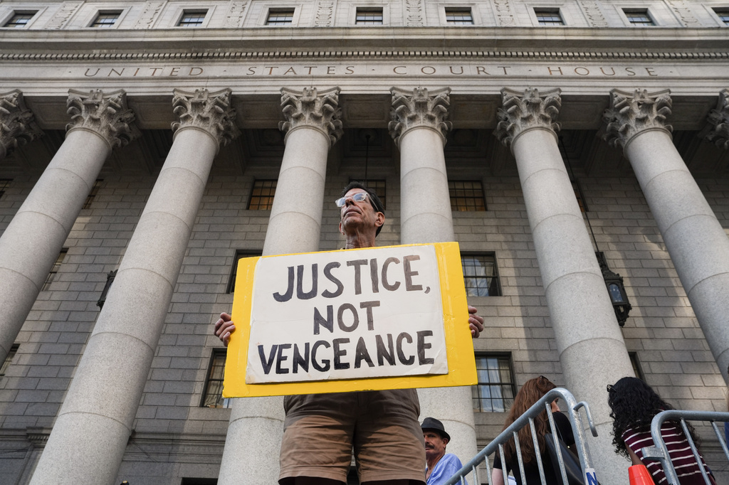 A man holds a sign outside of Manhattan Federal Court on the day of a hearing for Luigi Mangione on Friday, Aug. 14, 2026, in New York. (AP Photo/Ryan Murphy)