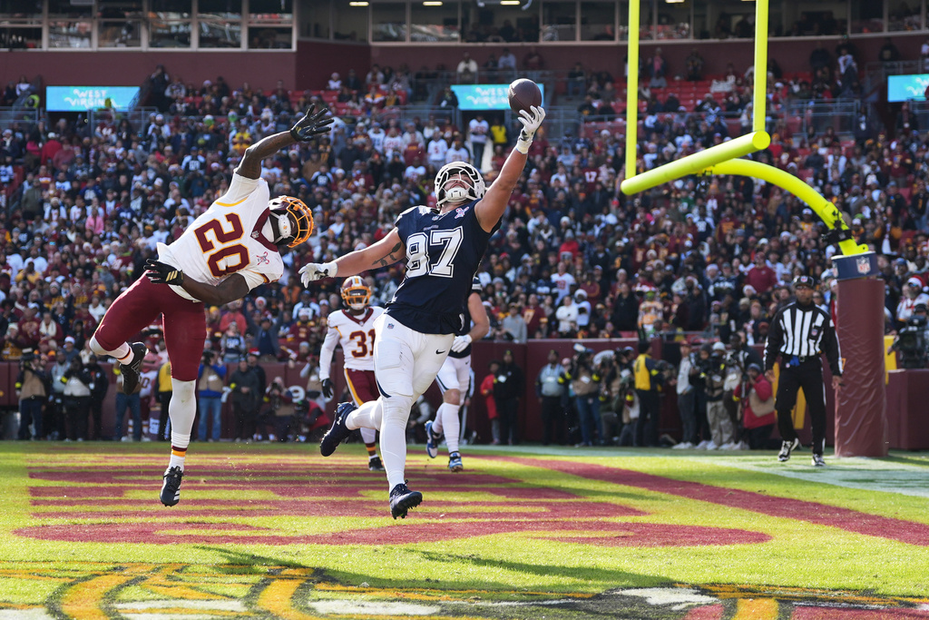 Dallas Cowboys tight end Jake Ferguson (87) catches a touchdown pass as Washington Commanders safety Quan Martin (20) defends during the first half an NFL football game Thursday, Dec. 25, 2025, in Landover, Md. (AP Photo/Stephanie Scarbrough)