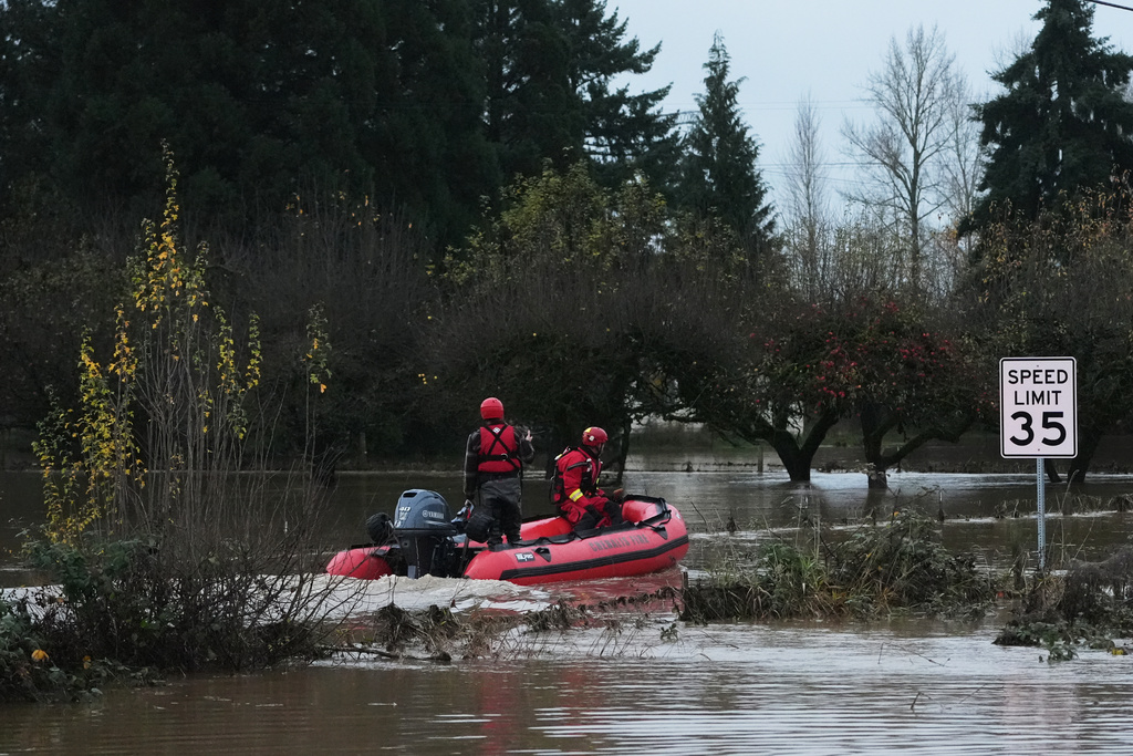 Rescue workers with Chehalis Fire venture into a flooded neighborhood to pick up evacuees after heavy rains, Tuesday, Dec. 9, 2025, in Chehalis, Wash. (AP Photo/Lindsey Wasson)