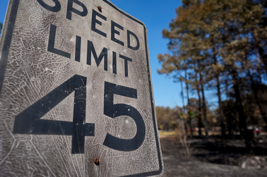 A burned speed limit sign stands near destroyed homes as the Brantley Highway 82 fire burns, Thursday, April 23, 2026, near Nahunta, Ga. (AP Photo/Mike Stewart)