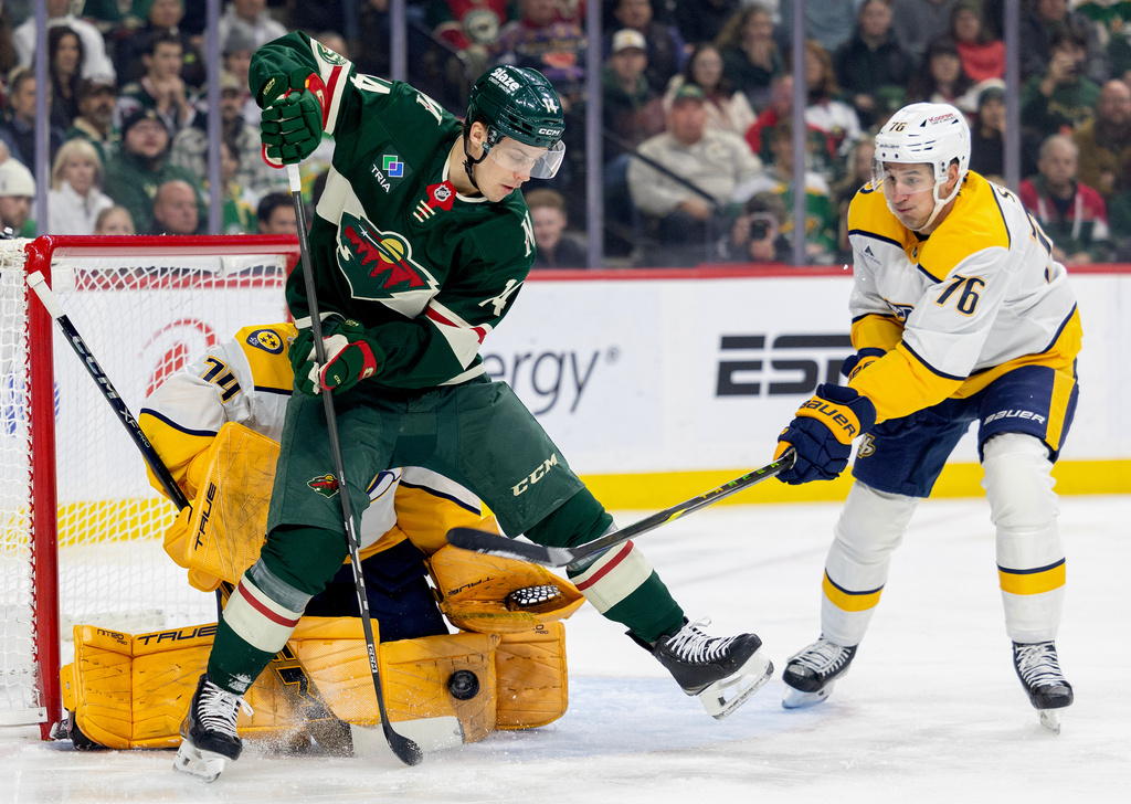 Minnesota Wild's Joel Eriksson Ek (14) tries to get the puck past Nashville Predators goalie Juuse Saros (74) as Predators's Brady Skjei (76) defends in the first period of an NHL hockey game against the Minnesota Wild, Tuesday, Dec. 23, 2025, in St. Paul, Minn. (Carlos Gonzalez/Star Tribune via AP)