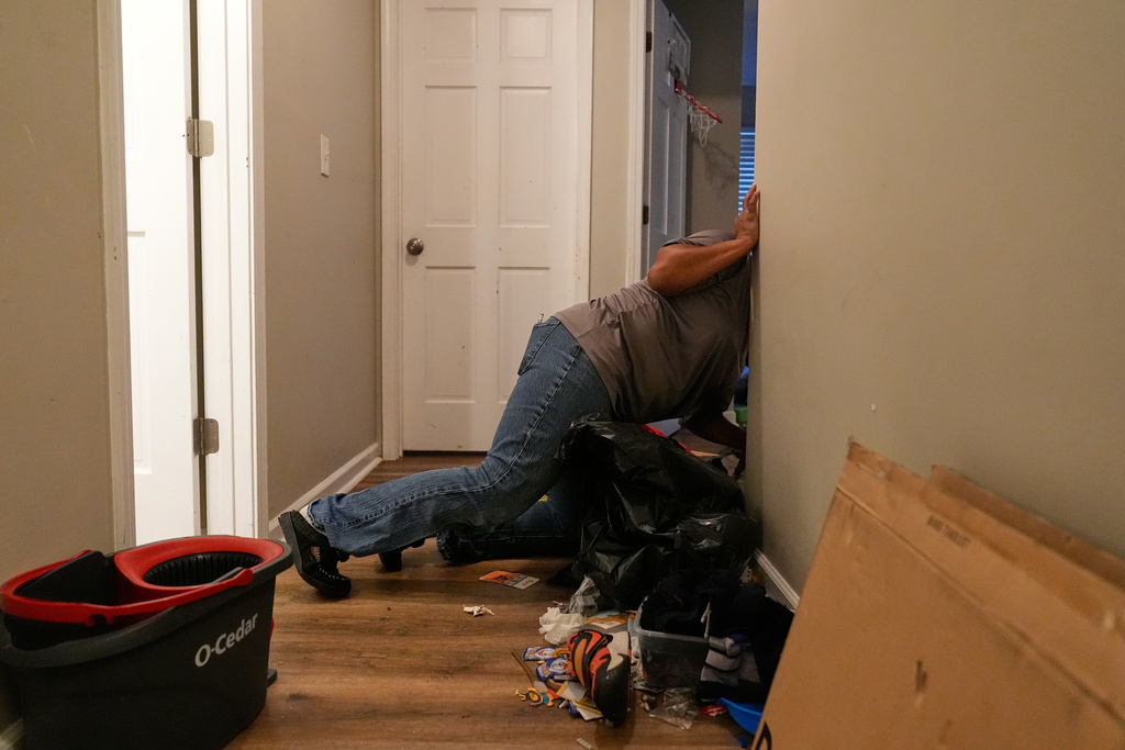 Sechita McNair cleans mold, toys and trash off the floor near the kids' rooms in their rental home on June 7, 2025, in Jonesboro, Ga. (AP Photo/Brynn Anderson)