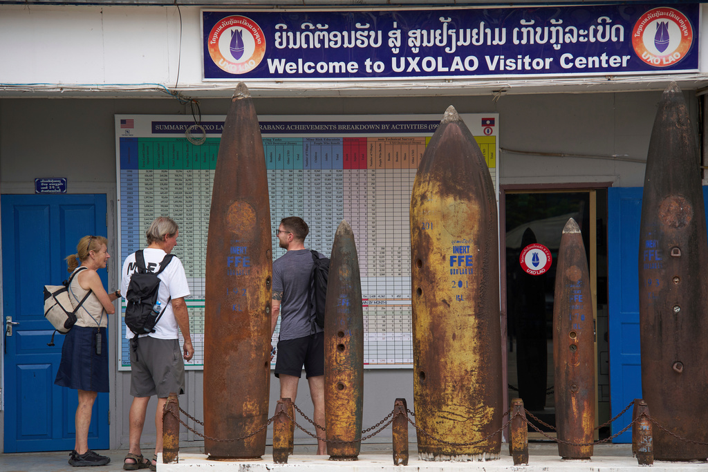 Visitors stand beside remnants of unexploded ordnance recovered during clearance operations at the UXO Lao Visitor Center in Luang Prabang, Laos, Monday, Nov. 3, 2025. (AP Photo/Eugene Hoshiko)