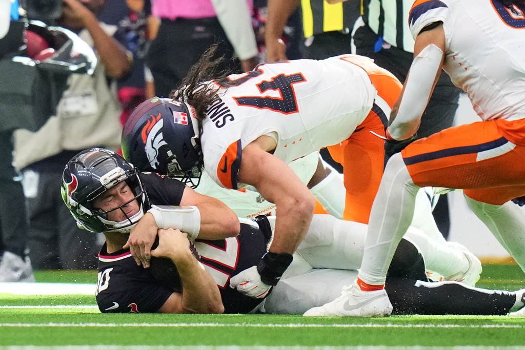 Houston Texans quarterback Davis Mills (10) runs the ball and comes to a sliding stop as Denver Broncos' Alex Singleton defends in the second half of an NFL football game Sunday, Nov. 2, 2025, in Houston. (AP Photo/Eric Gay)