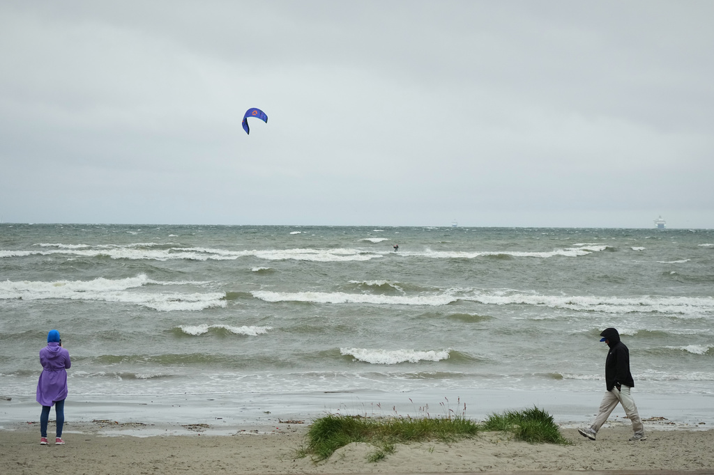 People walk at the beach along the Tallinn bay of the Baltic sea on a rainy and windy day in Tallinn, Estonia, Sunday, Aug. 23, 2026. (AP Photo/Sergei Grits)