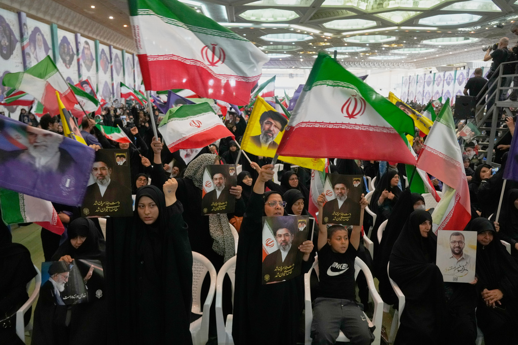 Government supporters hold Iranian flags and pictures of Iran's Supreme Leader, Ayatollah Mojtaba Khamenei, during a ceremony honoring the armed forces and those killed in the war with Israel and the U.S. at the Imam Khomeini Grand Mosque in Tehran, Iran, Sunday, May 24, 2026. (AP Photo/Vahid Salemi)