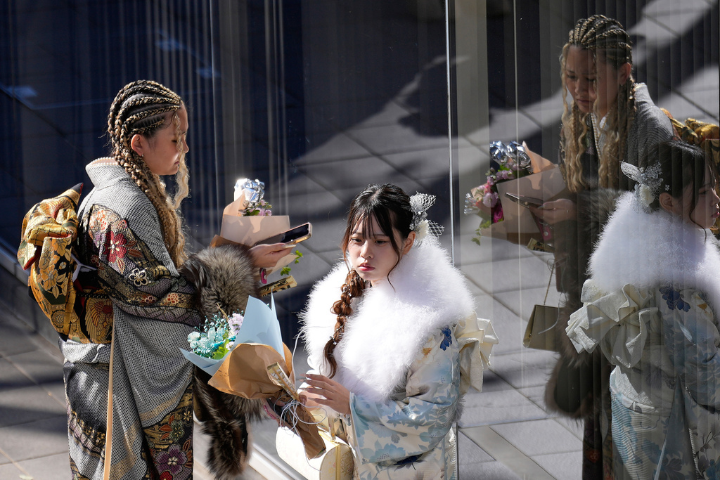Young adults pause after marking the Coming-of-Age Day, a centuries-old tradition and national holiday marking the milestone from childhood to adulthood, Monday, Jan. 12, 2026, in Yokohama near Tokyo. (AP Photo/Eugene Hoshiko)