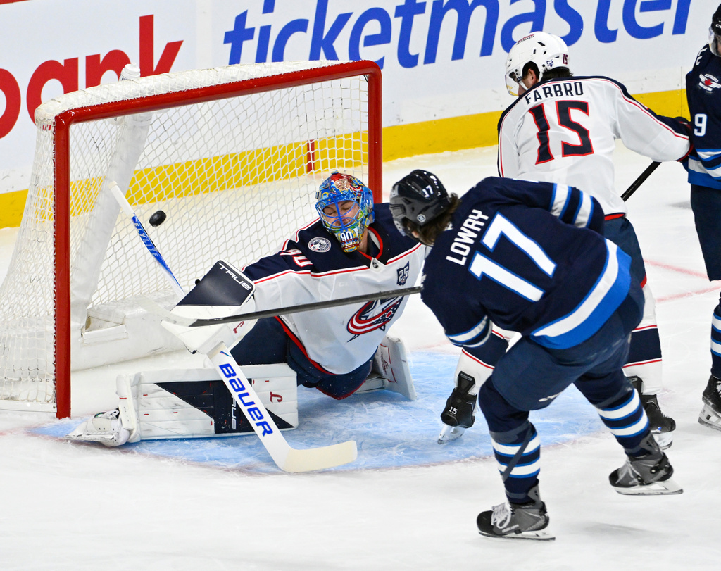 Winnipeg Jets' Adam Lowry (17) scores on Columbus Blue Jackets goaltender Elvis Merzlikins (90) during the first period of an NHL hockey game in Winnipeg, Manitoba, Tuesday Nov. 18, 2025. (Fred Greenslade/The Canadian Press via AP)