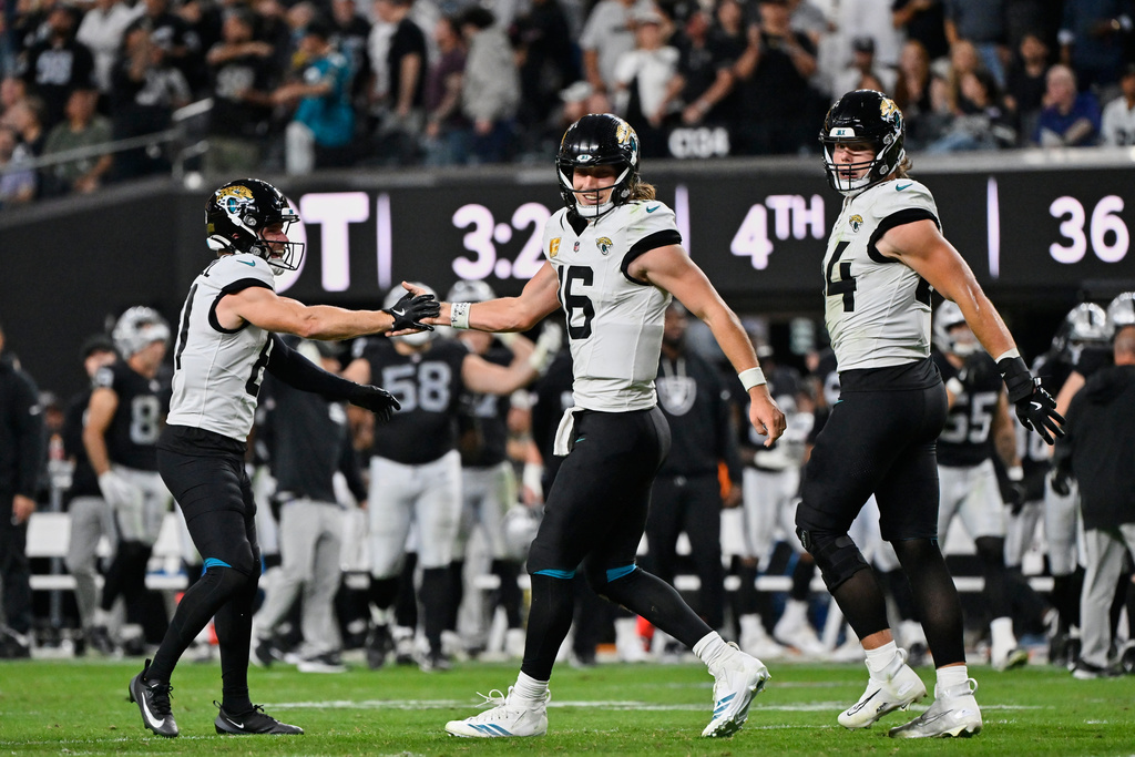 Jacksonville Jaguars quarterback Trevor Lawrence (16) celebrates with wide receiver Austin Trammell, left, after scoring a touchdown during overtime of an NFL football game against the Las Vegas Raiders, Sunday, Nov. 2, 2025, in Las Vegas. (AP Photo/David Becker)