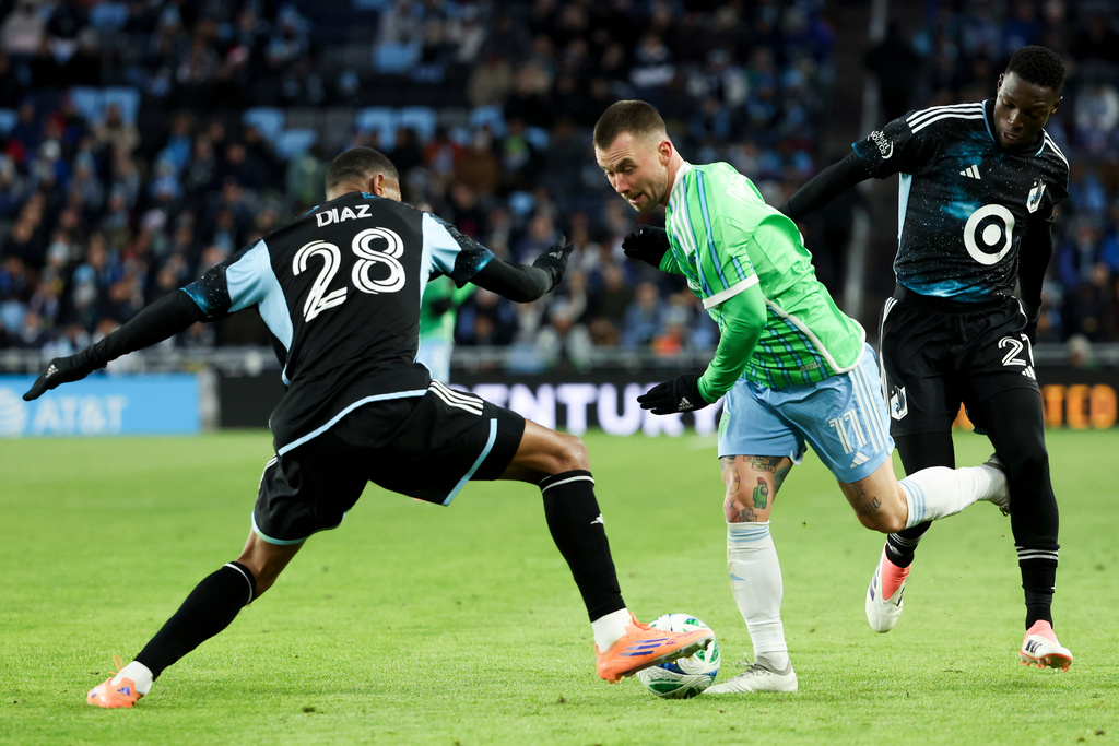 Minnesota United defender Jefferson Díaz (28) maneuvers the ball away from Seattle Sounders midfielder Albert Rusnák (11) while Minnesota United forward Mamadou Dieng, right, defends during the second half of Game 3 in the first round of MLS soccer's Western Conference playoffs in St. Paul, Minn., Saturday, Nov. 8, 2025. (AP Photo/Ellen Schmidt)