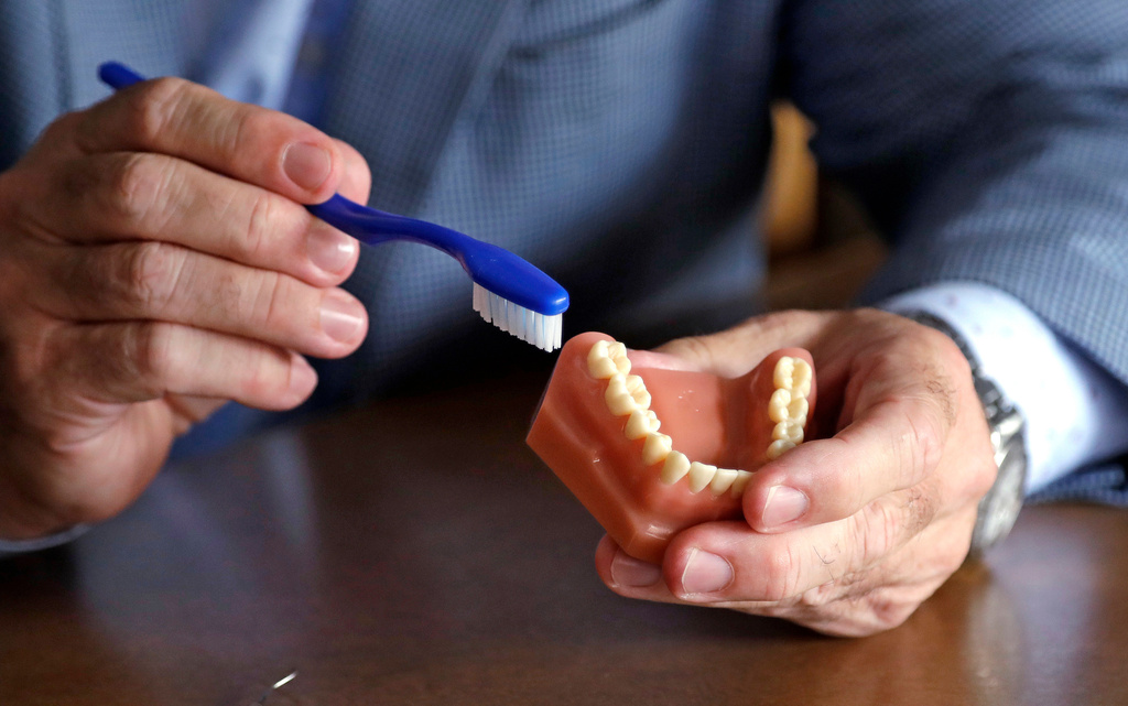 FILE - A dentist holds a model of teeth and a toothbrush at the University of Washington in Seattle on Aug. 3, 2018. (AP Photo/Elaine Thompson, File)