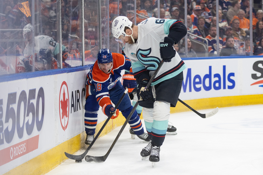 Seattle Kraken's Adam Larsson (6) and Edmonton Oilers' Zach Hyman (18) battle for the puck during the second period of an NHL game, in Edmonton, Tuesday March 31, 2026. (Jason Franson/The Canadian Press via AP)