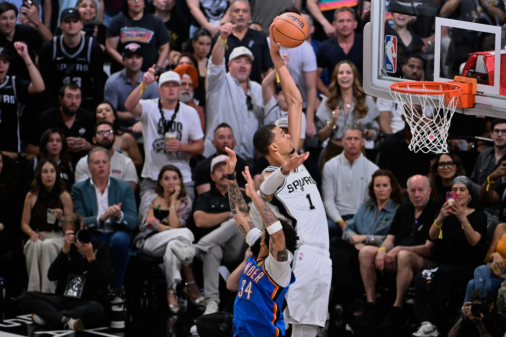 San Antonio Spurs forward Victor Wembanyama (1) dunks on Oklahoma City Thunder guard Kenrich Williams during the second half of Game 4 in the Western Conference finals NBA basketball playoffs series in San Antonio, Sunday, May 24, 2026. (AP Photo/Darren Abate)