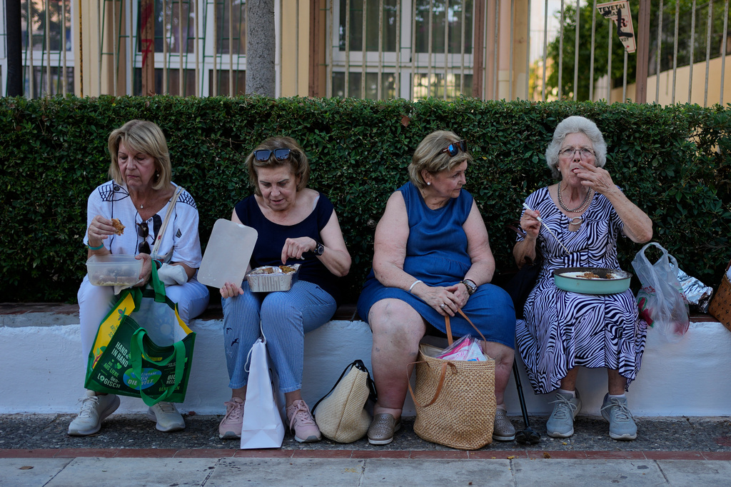 Pilgrims eat their Fanouropites, orange-flavored cakes, after a blessing at the Church of St. Fanourios in Athens, Wednesday, Aug. 26, 2026. (AP Photo/Thanassis Stavrakis)