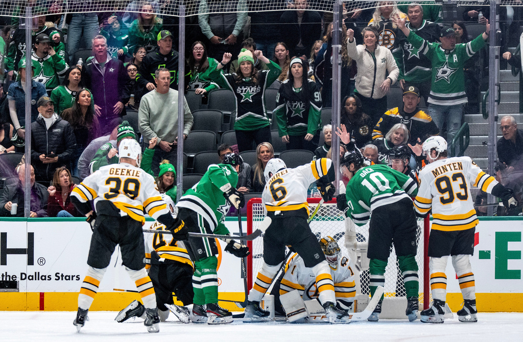 Dallas Stars left wing Jamie Benn, left, and center Oskar Bäck (10) look closely at a shot by Stars center Justin Hryckowian, not shown, as it slides past Boston Bruins goaltender Jeremy Swayman (1) and Bruins' Morgan Geekie (39), center Mark Kastelic (47), defenseman Mason Lohrei (6) and Fraser Minten (93) look on during the second period of an NHL hockey game, Tuesday, Jan. 20, 2026, in Dallas. (AP Photo/Jeffrey McWhorter)