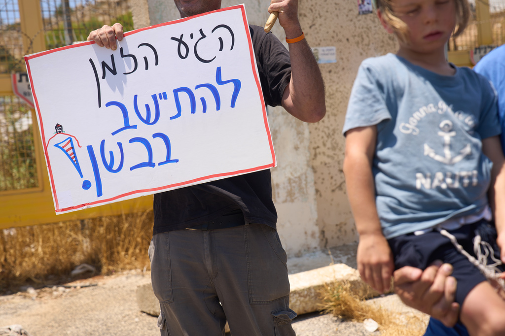 A right-wing Israeli activist holds a sign which reads "Its about time to settle in the Bashan", in the Israeli-occupied Golan Heights, Tuesday, July 21, 2026. (AP Photo/Ariel Schalit)