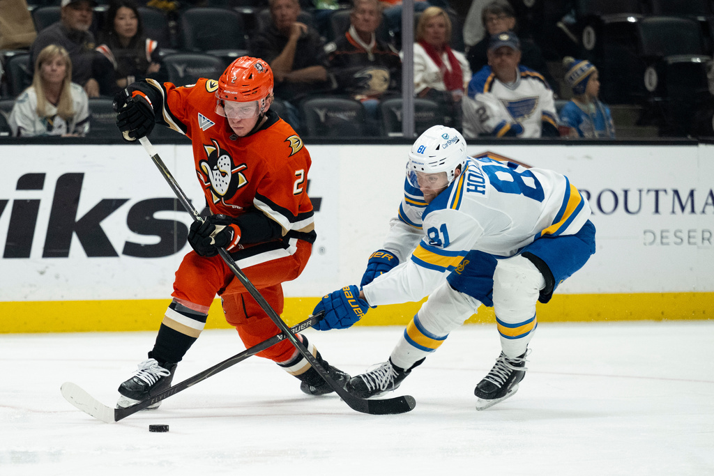 Anaheim Ducks defenseman Jackson LaCombe controls the puck away from St. Louis Blues left wing Dylan Holloway during the second period of an NHL hockey game, Sunday, March 8, 2026, in Anaheim, Calif. (AP Photo/Kyusung Gong)